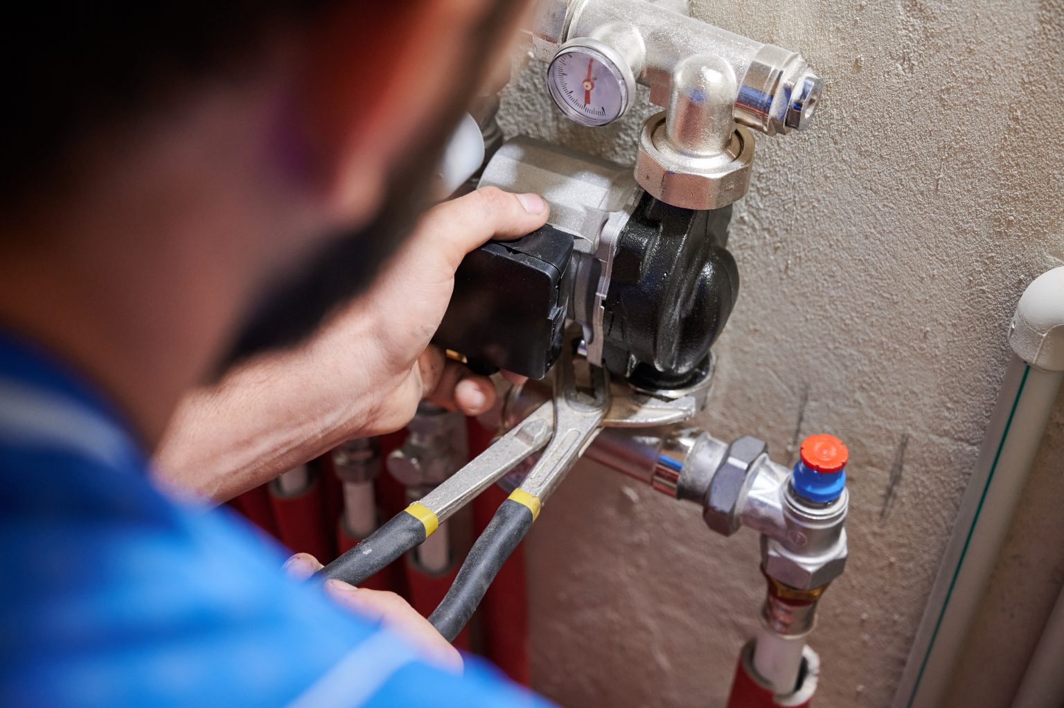 Close up of worker hands using wrenches, installing water pump in apartment. Man plumber working on heating system installation. Concept of radiator installation, plumbing works and home renovation.