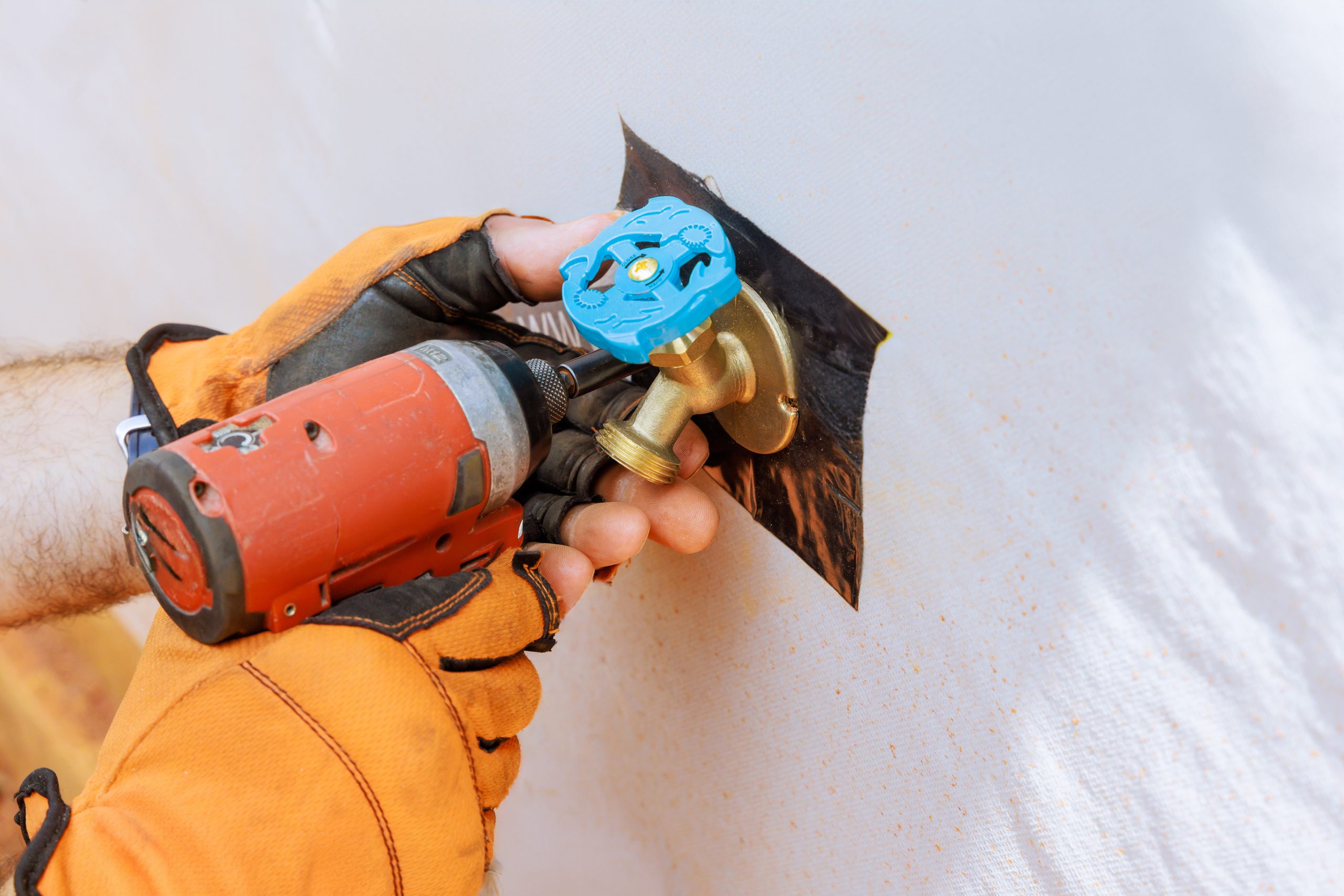 Plumber installs external water taps on house facade